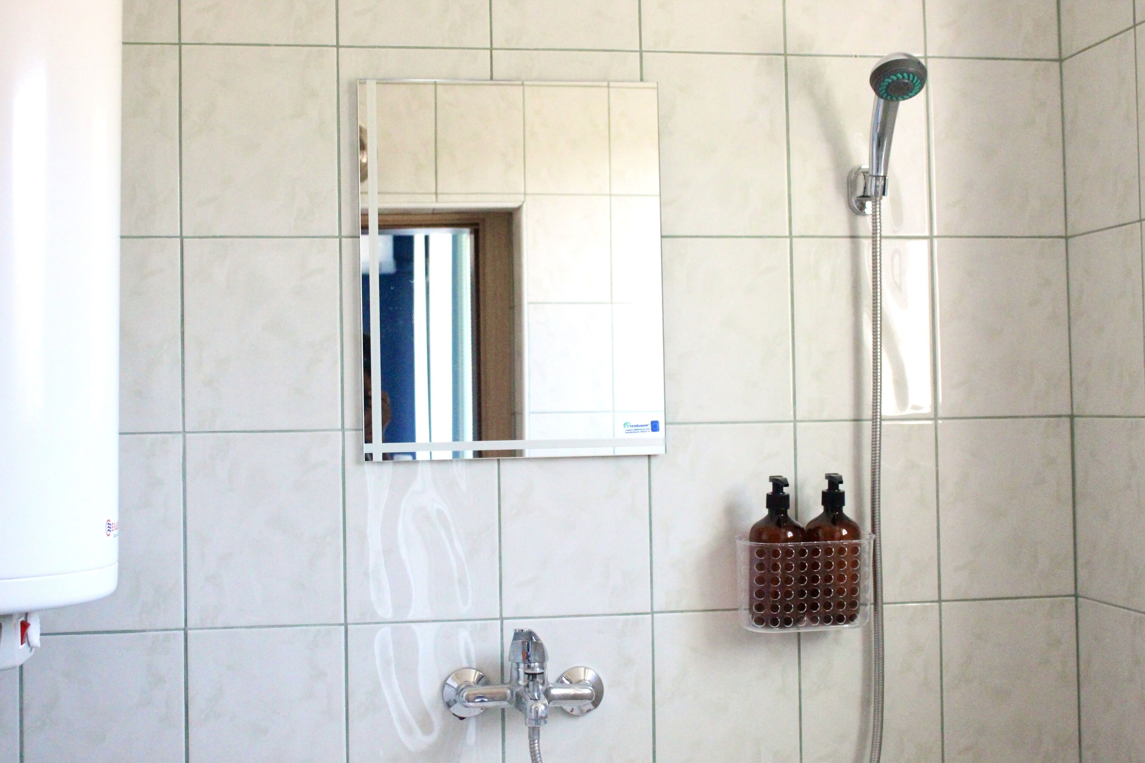 Un baño con ducha, espejo y dispensador de jabón.