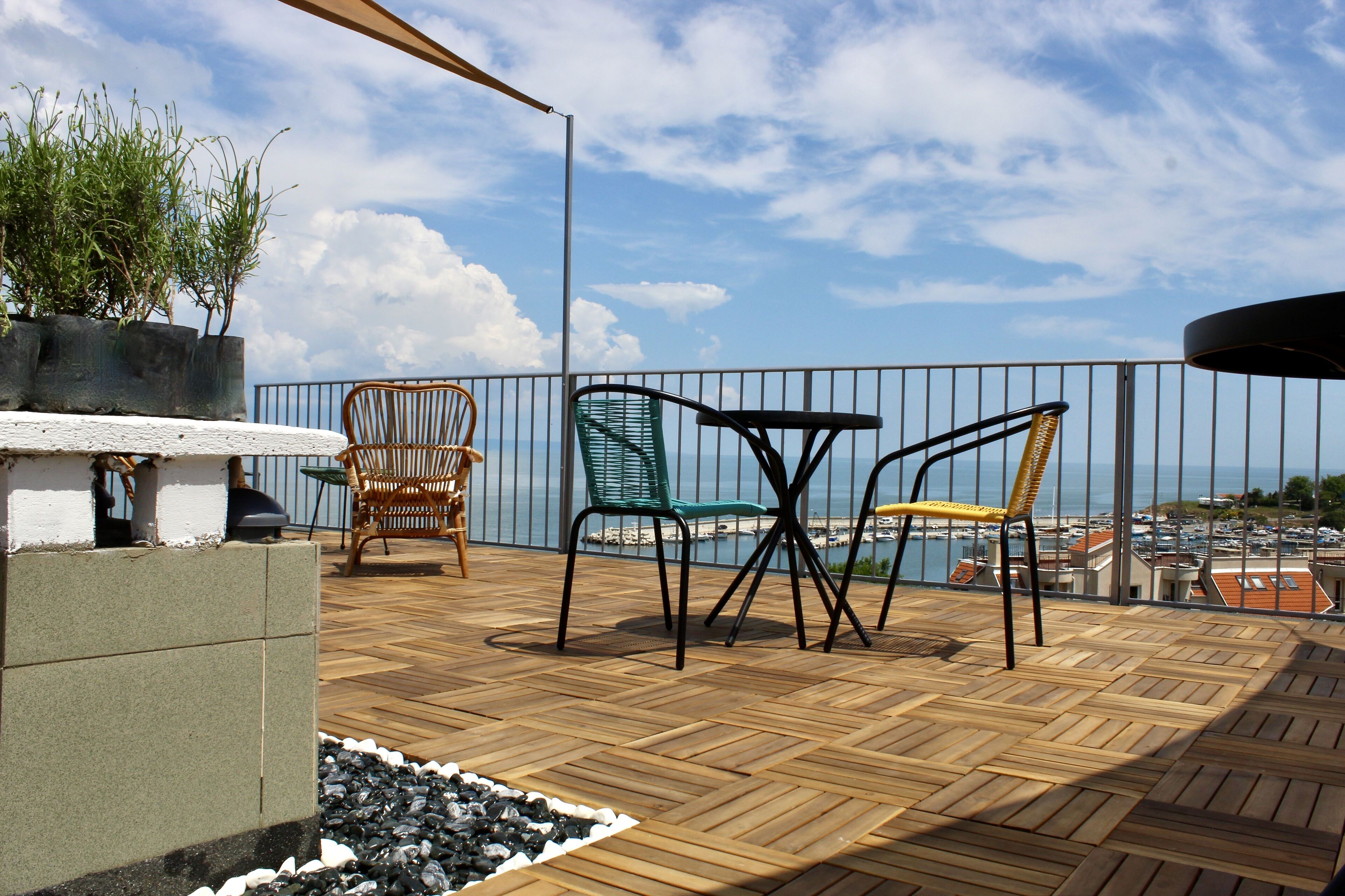 A wooden deck with outdoor furniture, a view of the sea, and a railing.