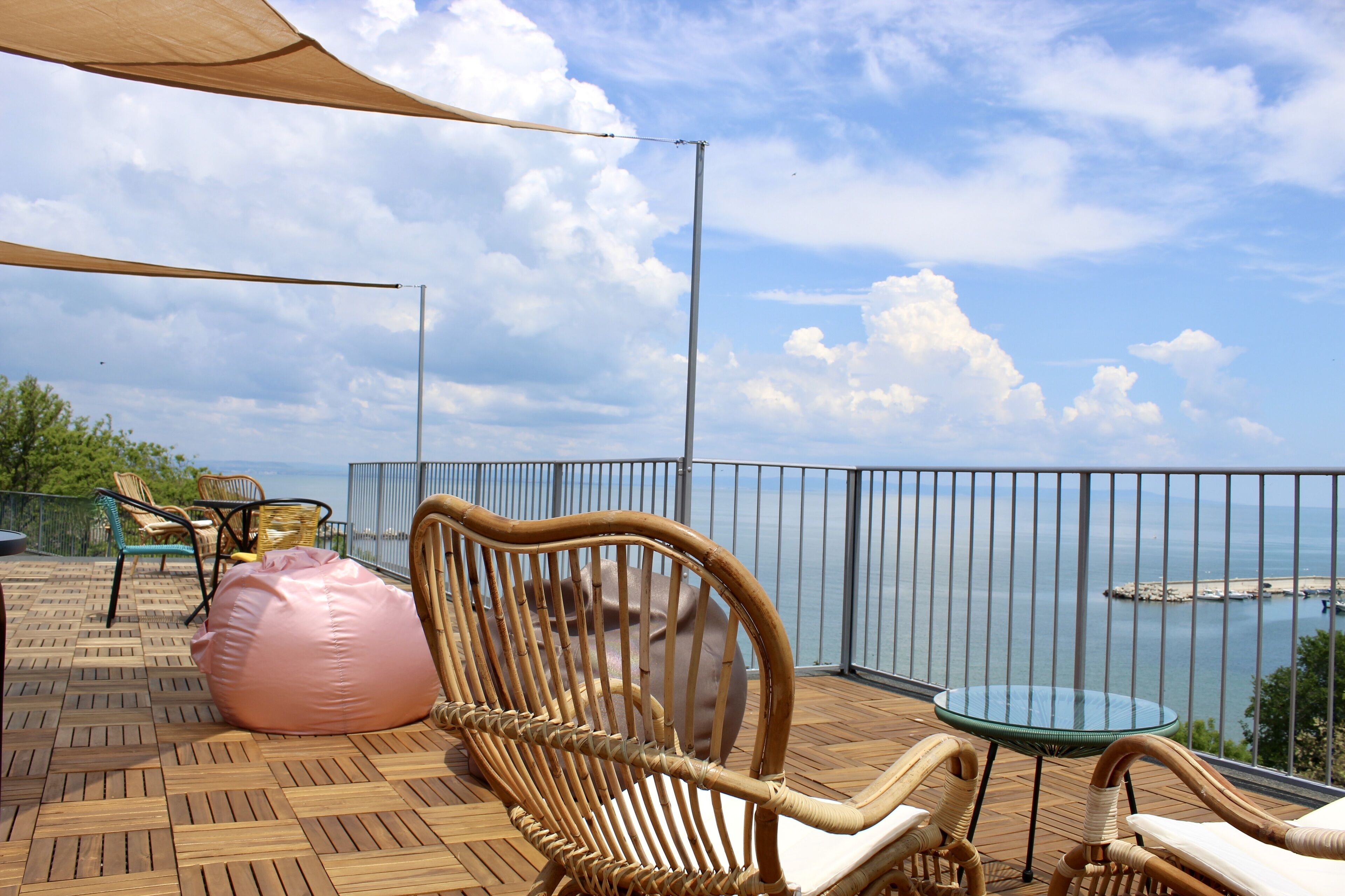 Un balcón con mobiliario de mimbre, una mesa de cristal y vista al mar.