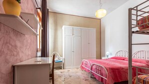 Ein Schlafzimmer mit Etagenbett, Schreibtisch, Stuhl und Kleiderschrank.