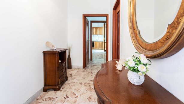 Ein Flur mit einem Holzschrank, einem Spiegel und einem Blumenstrauß.