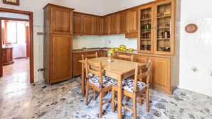 Eine Küche mit Holzausstattung, einem Esstisch mit Stühlen und einer gefliesten Spritzschutzwand.