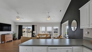 A modern kitchen with white cabinetry, a large island, and a dining area with a sofa and chairs.