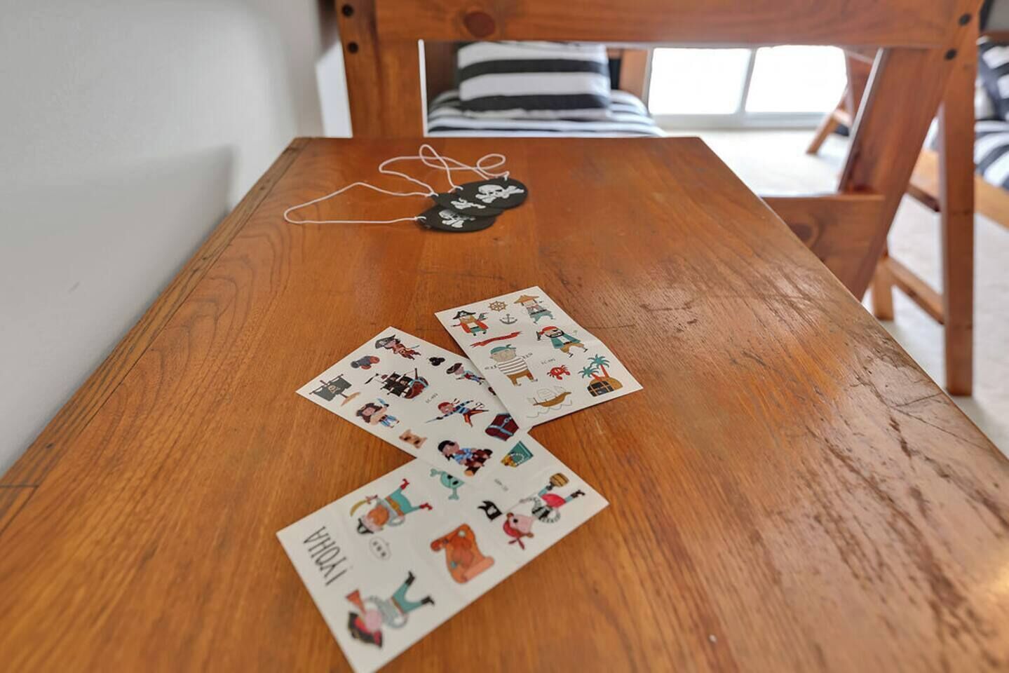 A wooden table with a black and white striped pillow on a wooden chair in the background.