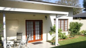 A single-story house with a covered porch, a front door with glass panels, and a small garden area with potted plants. - Whalesong guest house (St. Lucia)