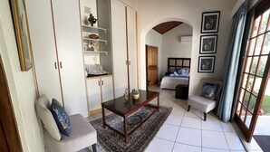 A spacious living room with a large window, a sofa, a coffee table, and a bed with a headboard. - Whalesong guest house (St. Lucia)