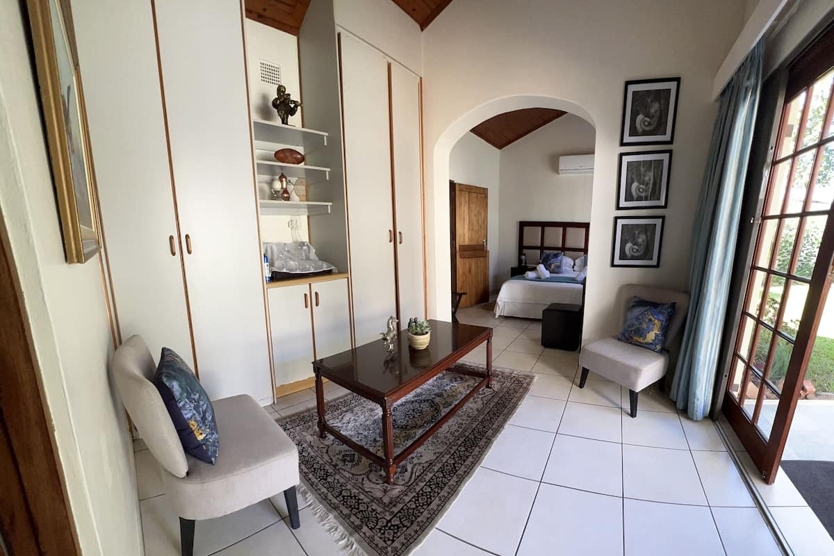 Uma sala de estar ampla com uma janela grande, um sofá, uma mesa de centro e uma cama com cabeceira.