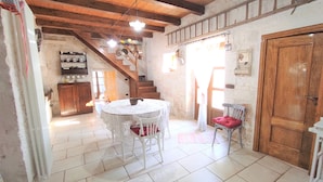 A rustic kitchen with a wooden staircase, a round table with chairs, and a wooden door. - CASA CICCONE CARDONE , trulli with Jacuzzi  and private parking lot  (Locorotondo)