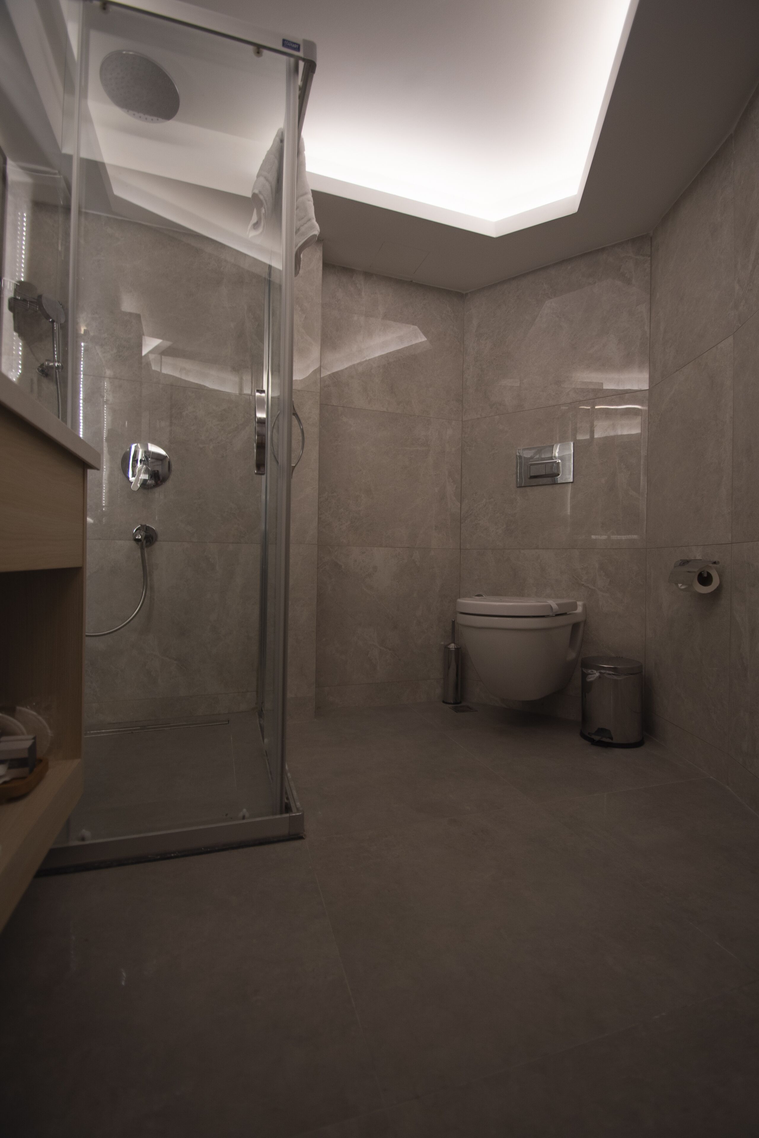 Une salle de bain moderne avec une douche à parois de verre, des toilettes et une poubelle.