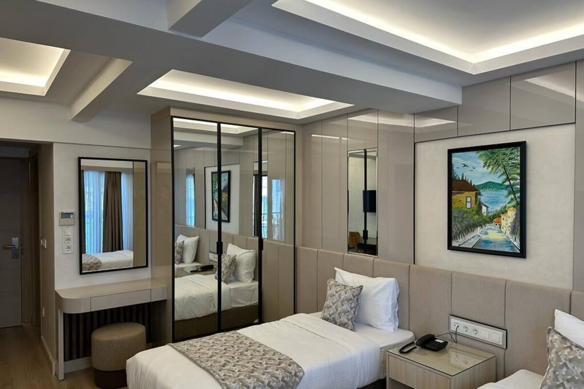 Ein Hotelzimmer mit Bett, Nachttisch und einem großen Spiegel, der den Raum reflektiert.