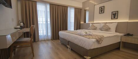 A modern hotel room with a large bed, a desk, and a chair.