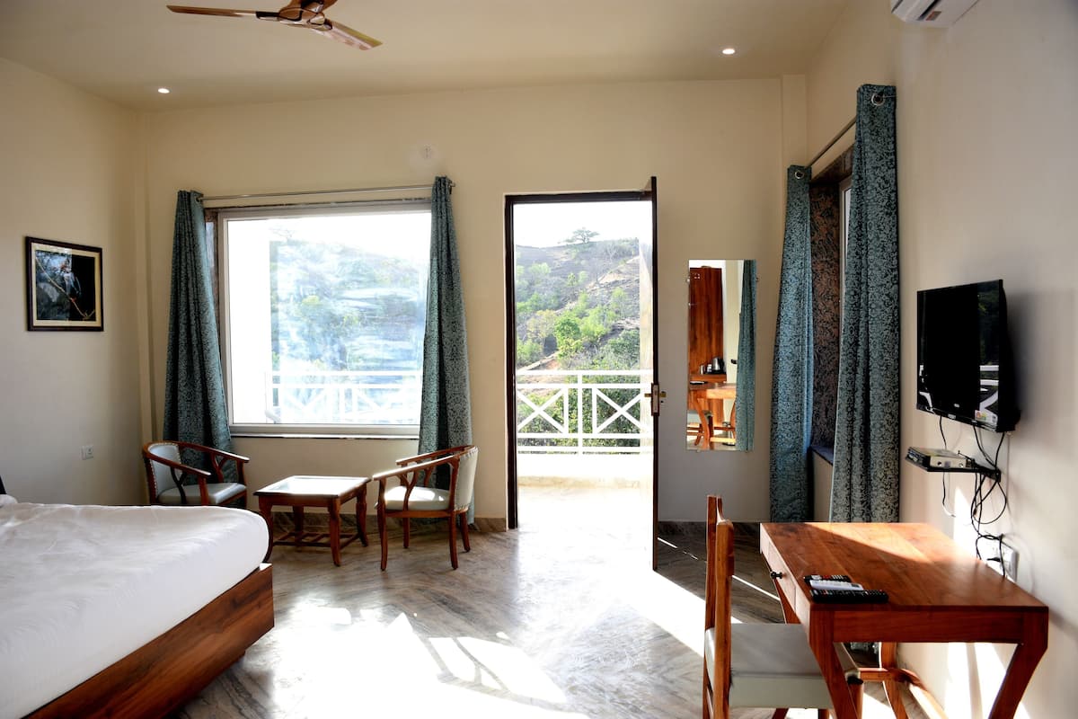 Ein Hotelzimmer mit Bett, Schreibtisch, Stuhl, Fernseher und einem Balkon mit Blick.