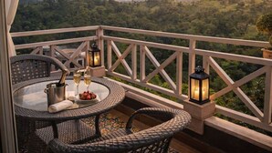 A balcony with wicker furniture, a glass table, and a bottle of champagne. - The Sky Imperial Pavoreal Jungle Resort (Kumbhalgarh)