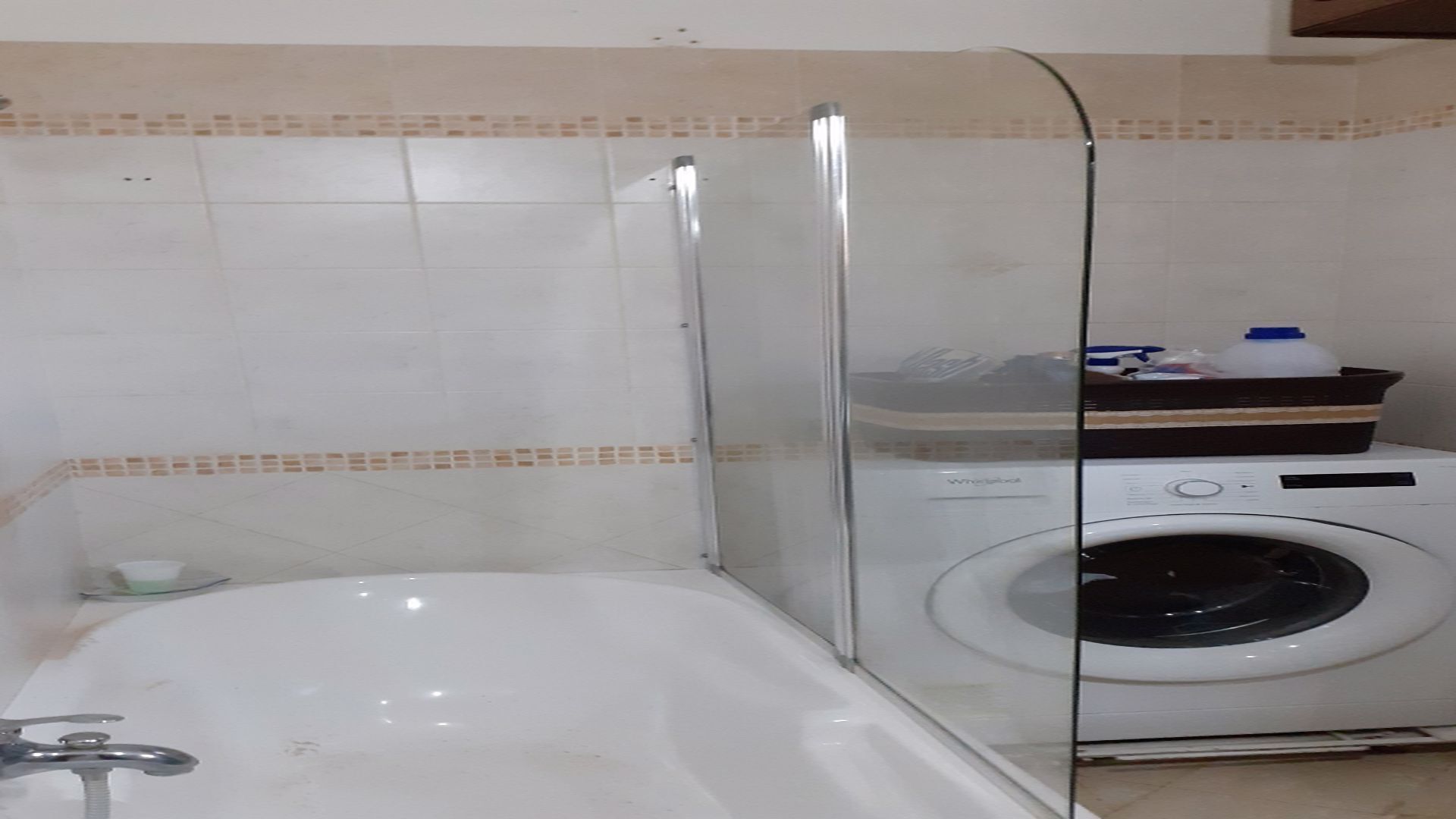 A bathroom with a white bathtub, a washing machine, and a shower enclosure.