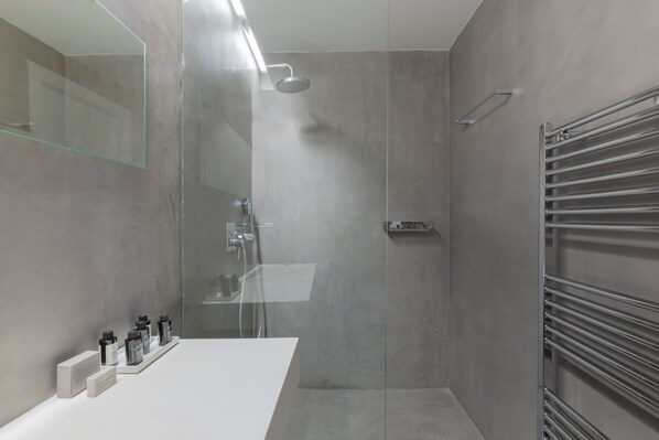 A modern bathroom with a glass-enclosed shower, a white sink, and a towel rack. - Elegant 2BR Apartment in Kolonaki (Athens)