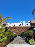 Un'area salotto esterna coperta con un cartello che riporta la scritta "bewiki" e un vialetto che conduce all'ingresso.