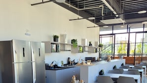 A modern kitchen with stainless steel appliances, a central island, and a dining area with grey chairs and a wooden table. - Bewiki (Florianópolis)