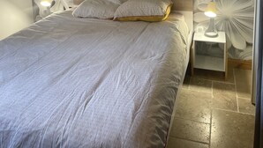 A bedroom with a large bed, two bedside lamps, and a wall with a leaf pattern. - 2 steps from the lake. (Parentis-en-Born)
