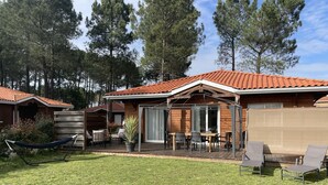 A wooden cabin with a tiled roof, a deck with outdoor furniture, and a hammock. - 2 steps from the lake. (Parentis-en-Born)