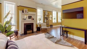 A spacious living room with a fireplace, a sofa, a coffee table, and a bookshelf. - Carolina Gold @ The Huntingdon Lofts Collection (Savannah)