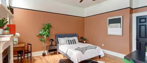 Un dormitorio moderno con cama, ventilador de techo, chimenea y alfombra de cuero de vaca.