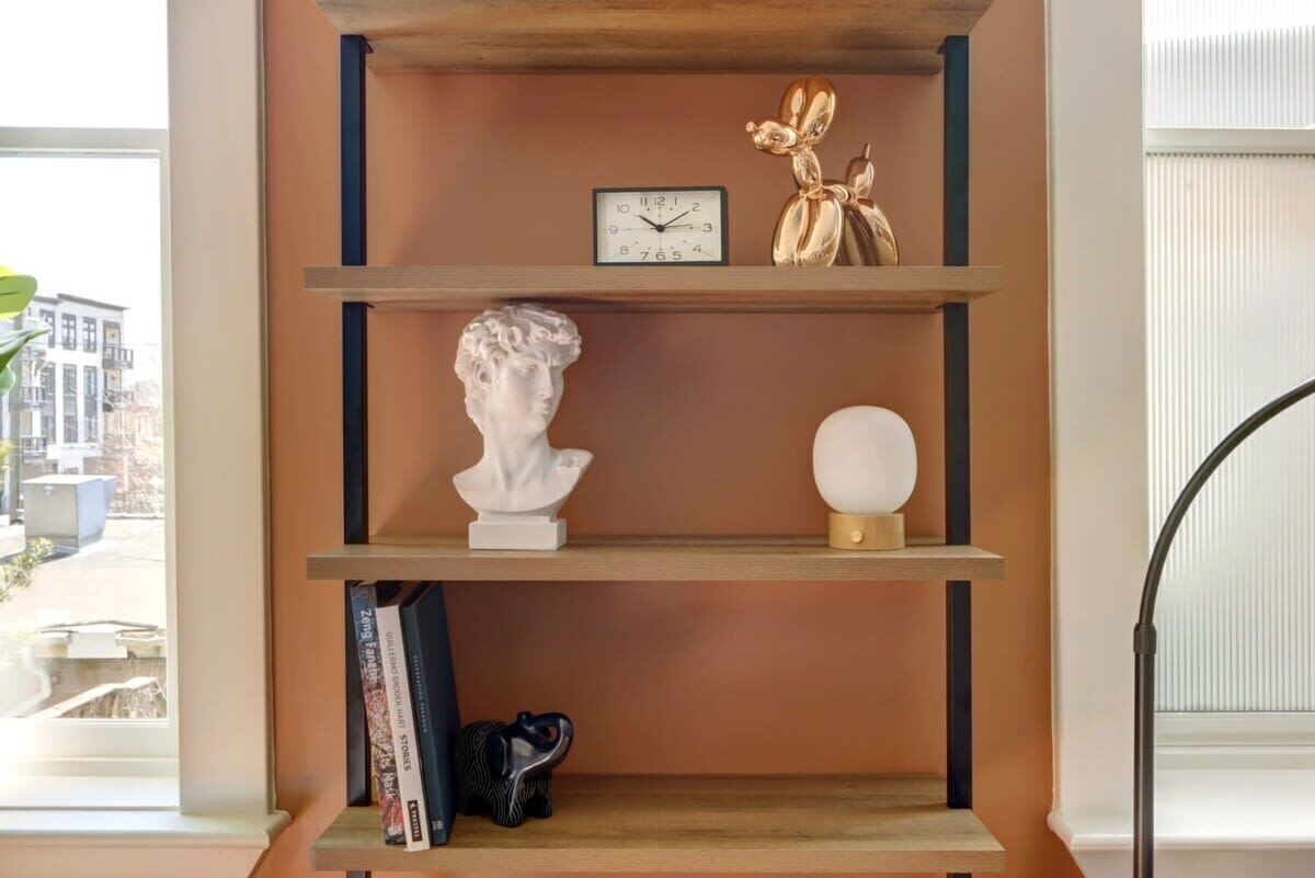 Una estantería con un reloj, un busto y objetos decorativos.