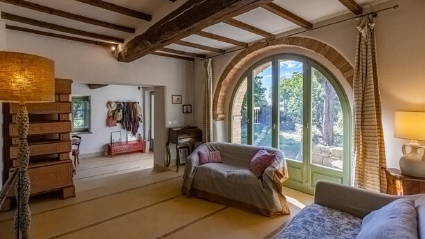 Ein gemütliches Zimmer mit einer Holztreppe, einem Sofa, einem Klavier und einem großen Bogenfenster.