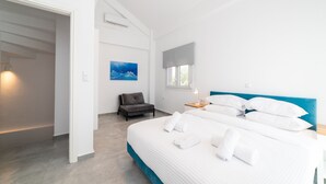Ein modernes Schlafzimmer mit einem großen Bett, einem Nachttisch, einem grauen Sofa und einem Bild an der Wand.