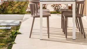 Eine Außenpatio mit Tisch und Stühlen, Blick auf ein Gebäude und einem klaren Himmel.