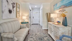 A hallway with a white door, a sofa, a patterned rug, and a cabinet with decorative items. - Family & Friends Paradise on the lake (Rockwell)