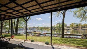 A covered outdoor area with a view of a lake, stone flooring, and a metal bench. - Family & Friends Paradise on the lake (Rockwell)