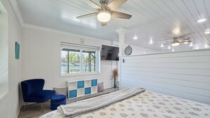 A bedroom with a bed, a blue chair, a TV, and a ceiling fan. - Family & Friends Paradise on the lake (Rockwell)