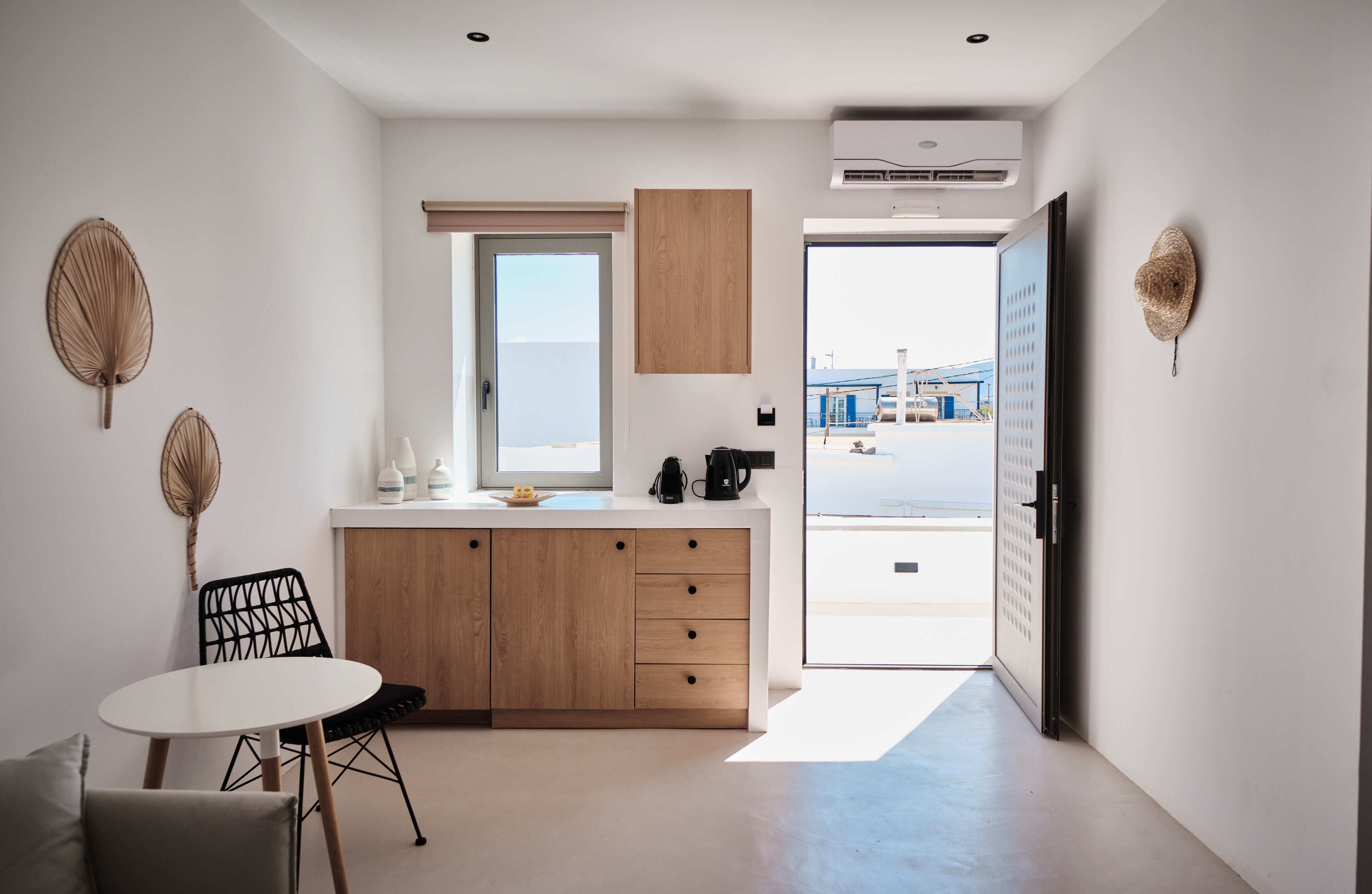 A modern kitchen with a wooden cabinet, a dining table with chairs, and a view of the outside.