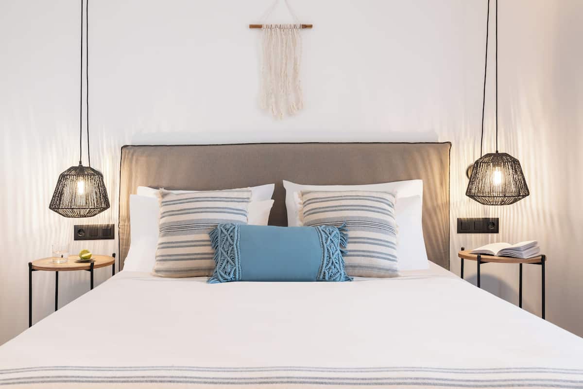 A neatly made bed with striped pillows, a blue accent pillow, and two bedside tables with lamps.