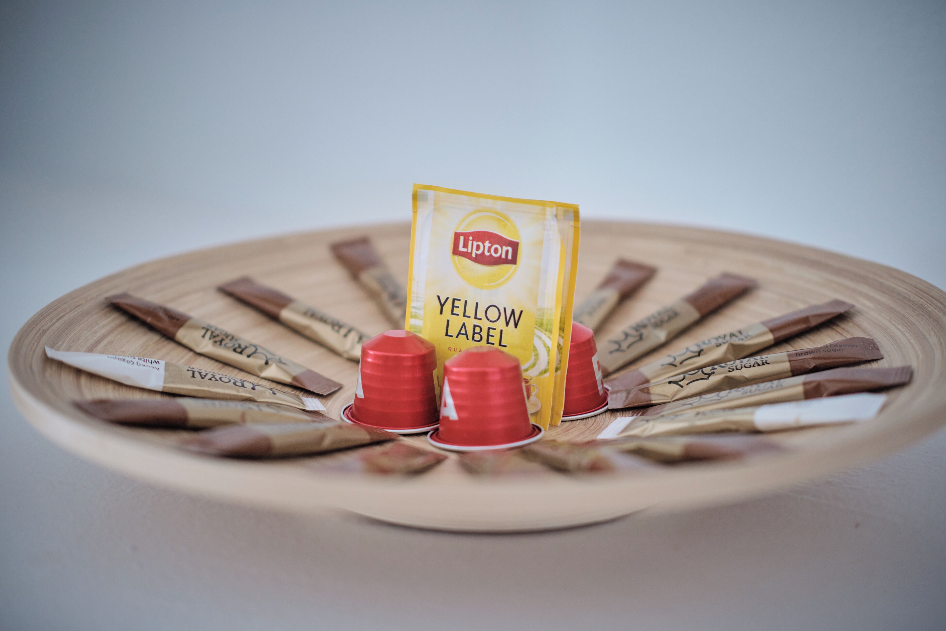 A wooden tray with Lipton Yellow Label tea bags and red cups.