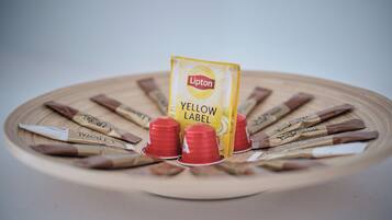 Una bandeja de madera con bolsitas de té Lipton Yellow Label y tazas rojas.