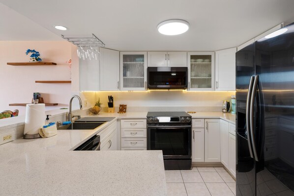 Una cocina moderna con armarios blancos, un refrigerador de acero inoxidable, horno empotrado y microondas.