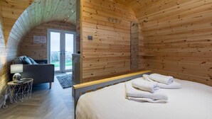 Acogedora habitación tipo cabaña de madera con una cama, una silla y una pequeña mesa.