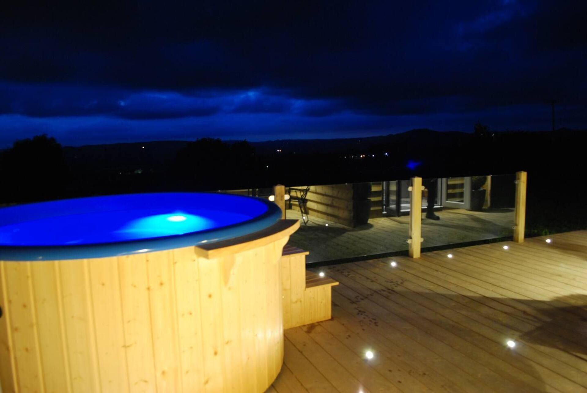 A wooden deck with a hot tub and a wooden structure in the background.