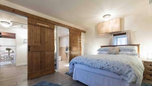A bedroom with a bed, wooden wardrobe, and a bathroom visible through an open door.