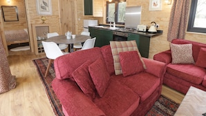 Interior acogedor de una cabaña con comedor, cocina y un sofá rojo.