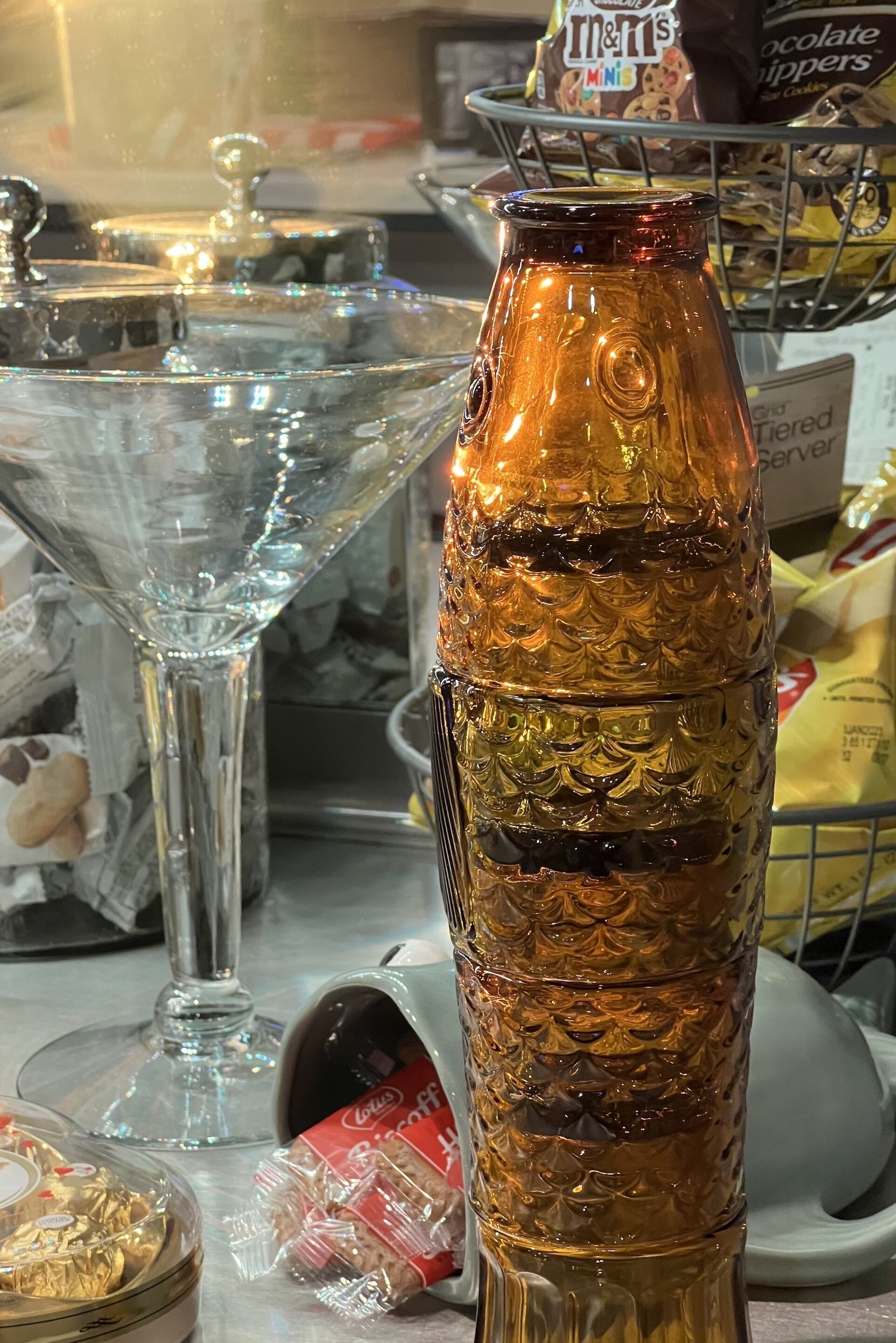 A table with a glass bottle, a martini glass, and a basket of snacks.