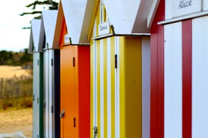 Una hilera de coloridas cabañas de playa con nombres en la parte superior.