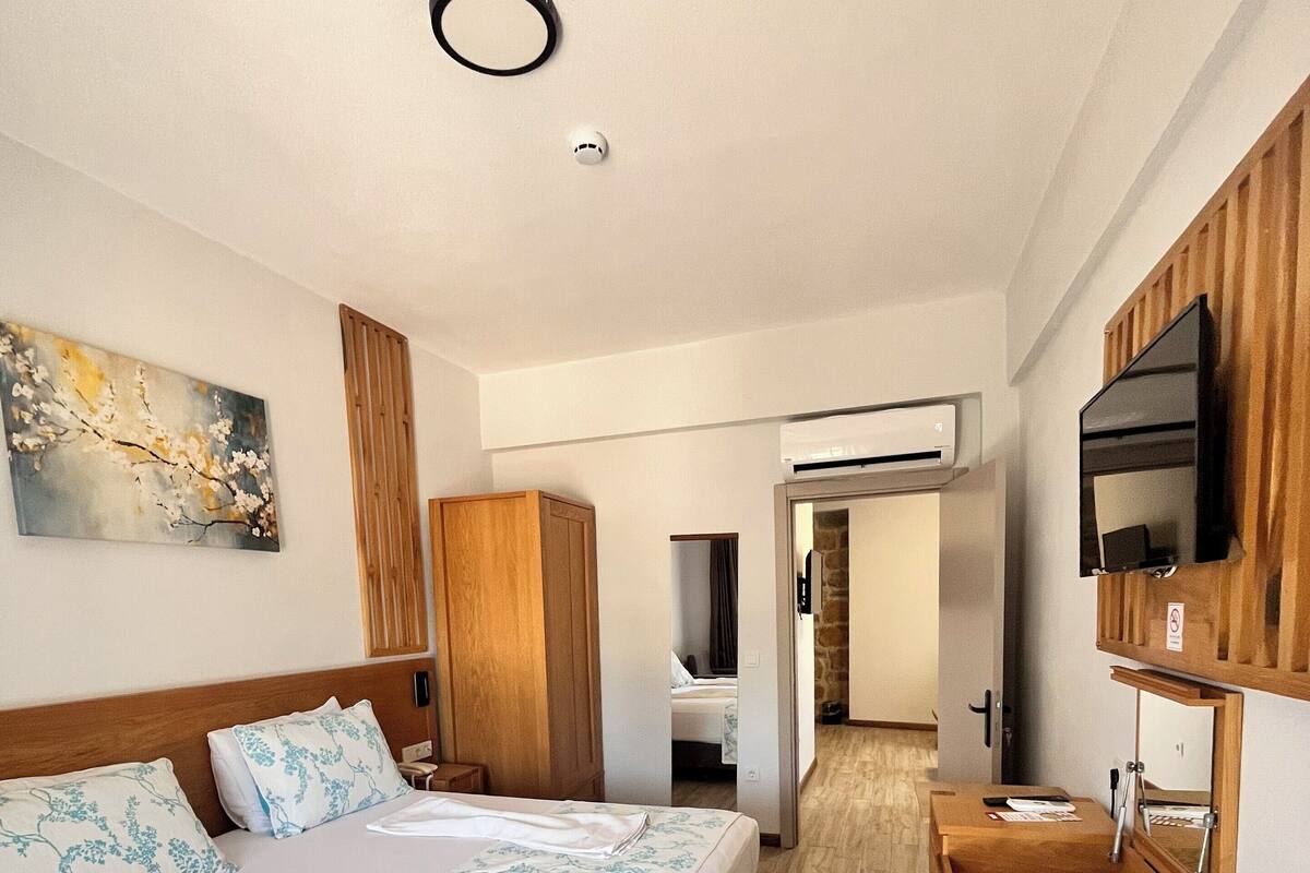 A hotel room with a large bed, a wooden desk, a television, and a painting on the wall.