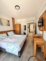Una habitación de hotel con una cama grande, un escritorio de madera, un televisor y un cuadro en la pared.