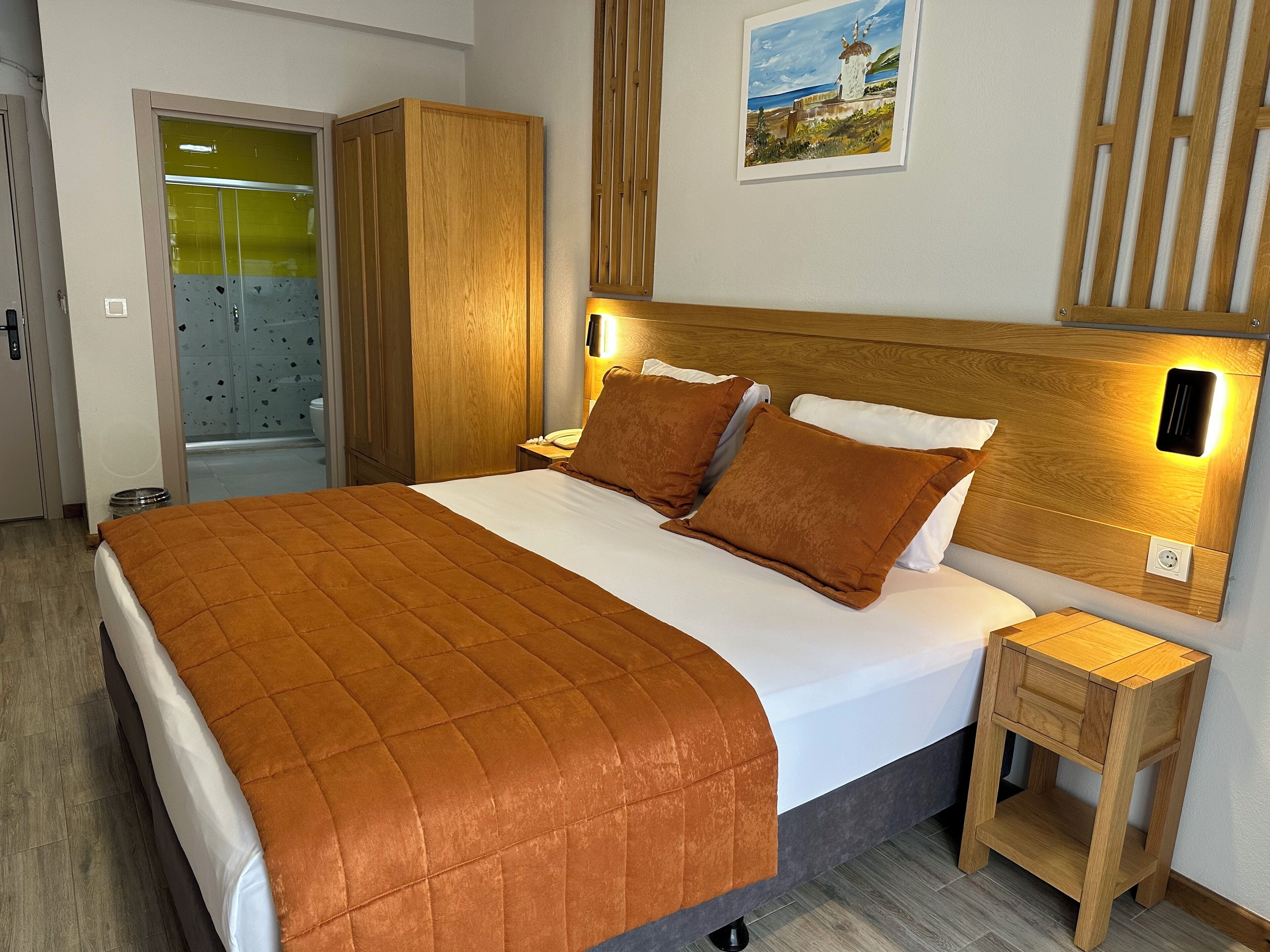 A neatly made bed with a brown quilt, wooden headboard, and bedside lamps.