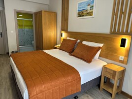 Una cama bien tendida con un edredón marrón, cabecera de madera y lámparas de noche.