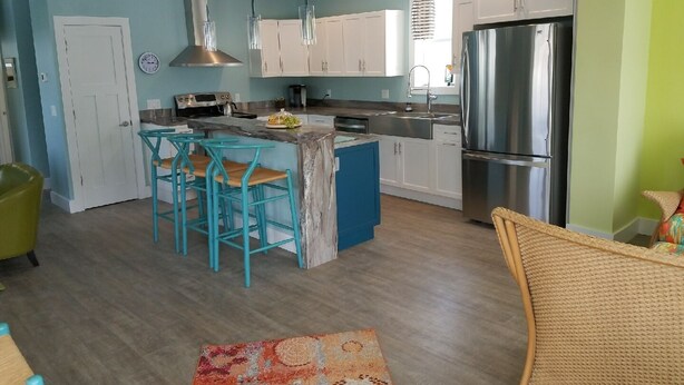 Una cocina moderna con armarios blancos, un refrigerador de acero inoxidable y una isla azul con taburetes de bar.
