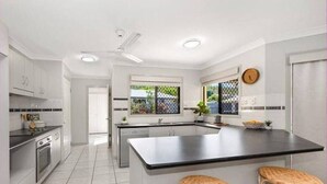 Una cocina moderna con armarios blancos, una isla grande con taburetes y un ventanal con vistas.