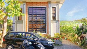 Una casa moderna con un gran portón de garaje, un coche negro y una motocicleta estacionadas al frente.
